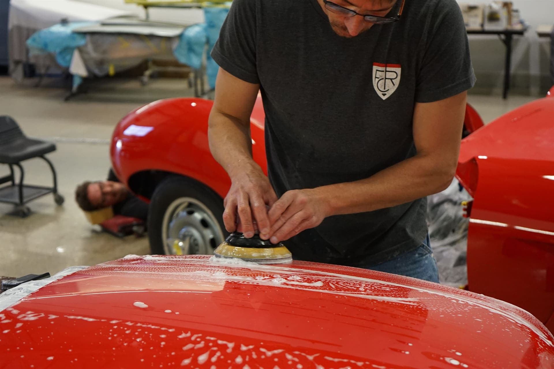 Farland craftsman hand-finishing paint on a red Arnolt-Bristol
